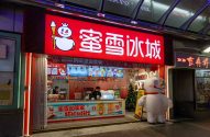 Loja Mixue Bingcheng com letreiro vermelho e seu mascote boneco de neve (um no letreiro e um inflável).