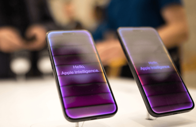 Dois iPhones exibindo "Hello, Apple Intelligence" em suas telas roxas, em um mostruário de loja.