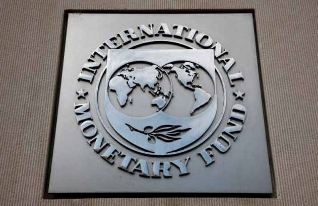 Sinal metálico do Fundo Monetário Internacional (FMI) com mapa-múndi e a inscrição 'International Monetary Fund'.