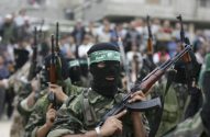 Grupo de homens de balaclava preta e uniformes camuflados, empunhando fuzis. Um usa faixa verde na cabeça.