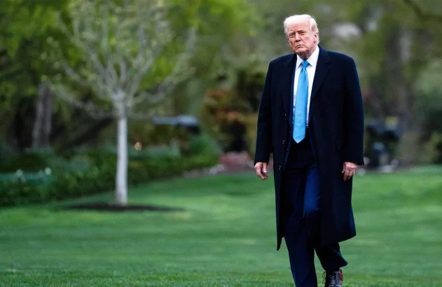 Trump está de terno preto e gravata azul e caminha para falar com jornalistas sobre as tarifas