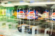 Refrigerador de loja com garrafas de Pepsi, incluindo o sabor Wild Cherry & Cream. Outros refrigerantes e sinal de preço.