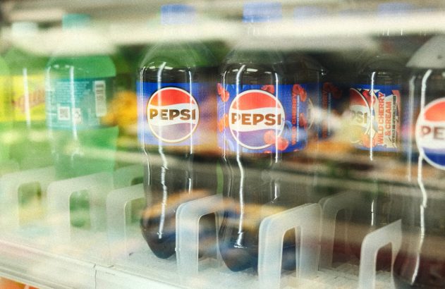 Refrigerador de loja com garrafas de Pepsi, incluindo o sabor Wild Cherry & Cream. Outros refrigerantes e sinal de preço.