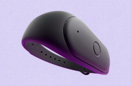 Dispositivo vestível escuro e liso, com pulseira, sobre fundo roxo.