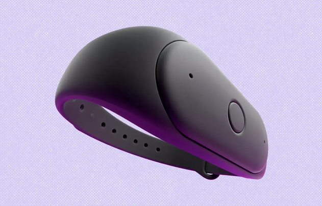 Dispositivo vestível escuro e liso, com pulseira, sobre fundo roxo.