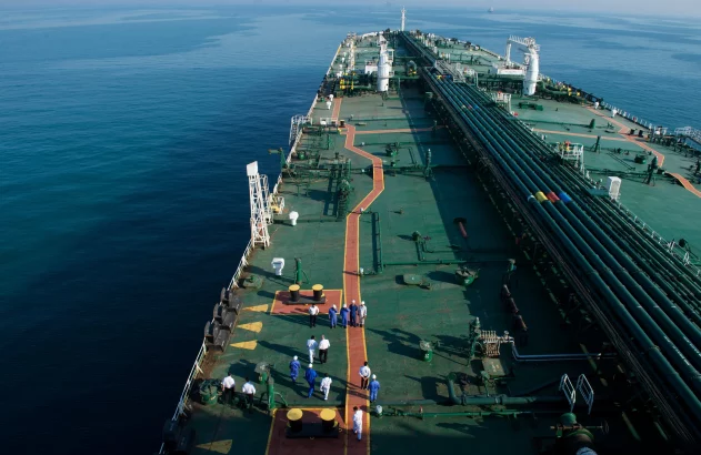 Navio-tanque no mar, com tubulações visíveis e pessoas caminhando no convés.