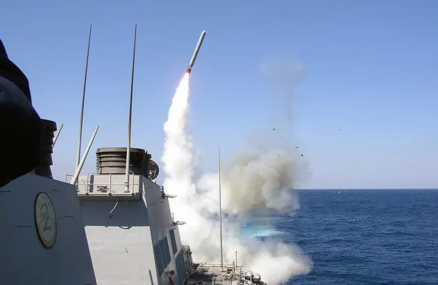 Míssil é lançado de um navio de guerra no mar, com fumaça e água espirrando.