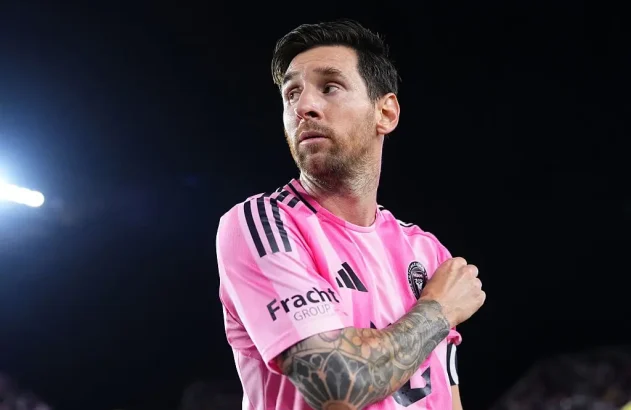 Lionel Messi em campo com camisa rosa do Inter Miami, olhando.