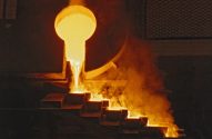 Metal fundido é vazado de uma concha em moldes escalonados, em processo industrial.