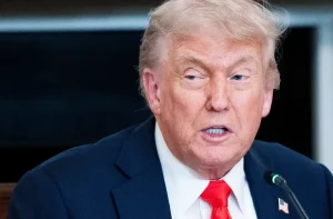 Donald Trump está com blazer azul escuro, camisa branca e gravata vermelha
