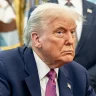 Trump está de terno azul e gravata roxa, olhando de lado, com cara de enfezado