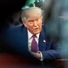 Donald Trump está com um terno azul, gravata roxa, olhando feroz para o lado direito da câmera