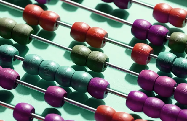 Ábaco com fileiras de contas de madeira coloridas em hastes metálicas. Contas em roxo, vermelho, verde e azul-turquesa contrastam com fundo verde claro.