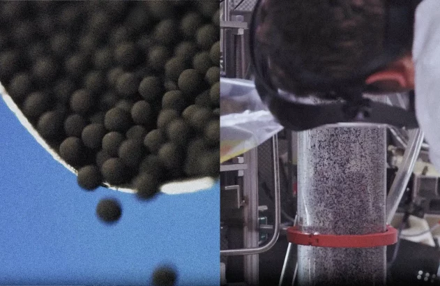 Pelotas pretas caindo de um recipiente. Ao lado, um cientista com óculos de proteção inclinado sobre um tubo cheio de grânulos.