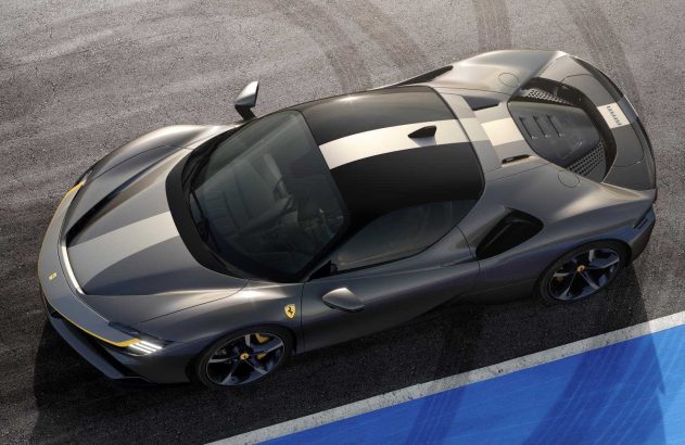 Ferrari cinza-escuro com faixas claras e detalhes amarelos, vista de cima em pista com linha azul e branca.