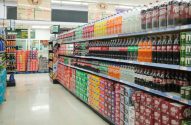 Corredor de supermercado com prateleiras cheias de bebidas em garrafas e caixas.