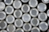 Muitas tampas de latas de alumínio prateadas, vistas de cima e agrupadas.