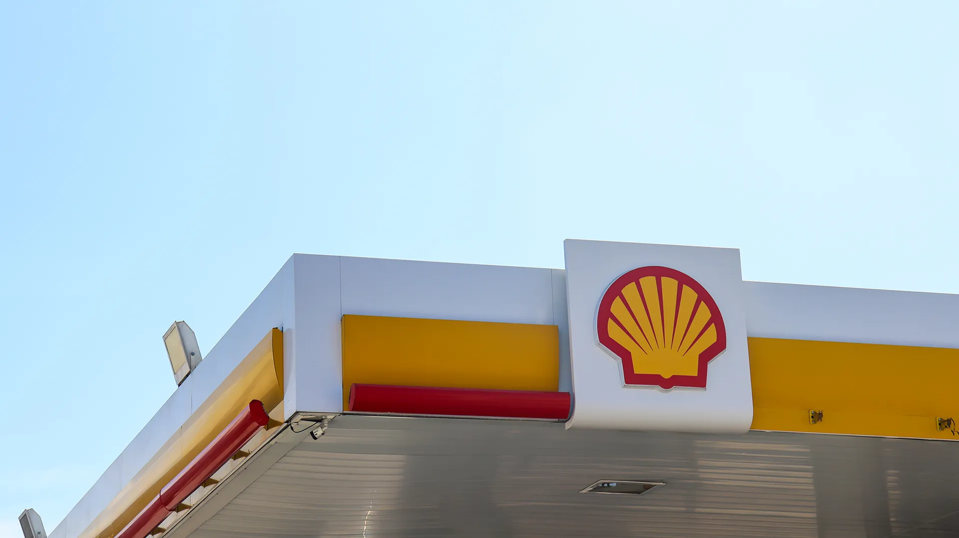 Imagem da fachada de um posto de gasolina com o céu azul ao fundo