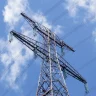 Topo de uma torre de transmissão de energia elétrica contra um céu azul
