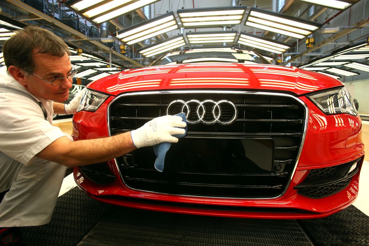 foto de uma mão com uma luva branca, limpando o logo de um Audi vermelho