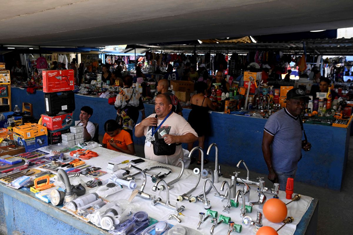 Foto ce um comerciante vendendo peças de casa, como torneiras, em uma feira em Cuba