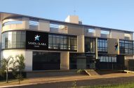 Fachada do Grupo Santa Clara: um predio baixo, de dois andares, cinza com a logomarca numa placa preta