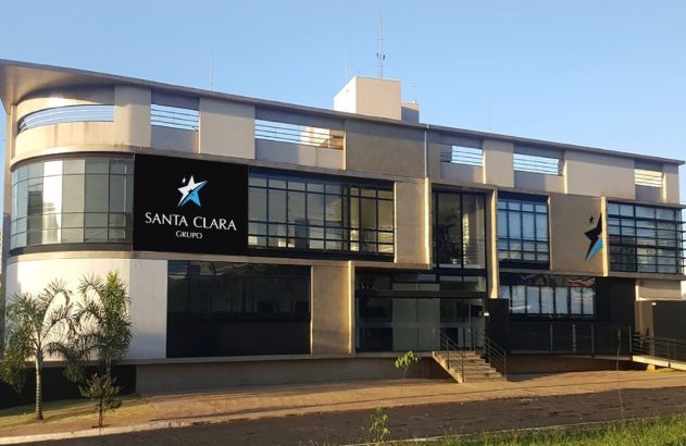 Fachada do Grupo Santa Clara: um predio baixo, de dois andares, cinza com a logomarca numa placa preta