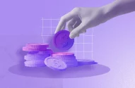 A imagem mostra um fundo roxo claro com textura granulada e uma pilha de moedas em roxo e rosa, destacando o símbolo de cifrão. Ao fundo, um gráfico de linhas e uma mão posicionando uma moeda no topo sugerem temas de investimento e economia.