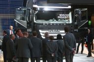 Imagem de homens de terno preto olhando para um caminhão da Iveco