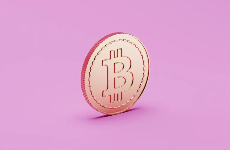 A imagem apresenta uma moeda com o símbolo do Bitcoin em destaque, posicionada sobre um fundo rosa sólido. A moeda possui um brilho metálico característico, com entalhes na borda e sombra ao fundo, enfatizando seu relevo e detalhes.