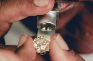 Funcionário usa uma lupa para inspecionar um diamante natural polido em uma oficina no Diamond District de Londres, especializada em joias sob medida