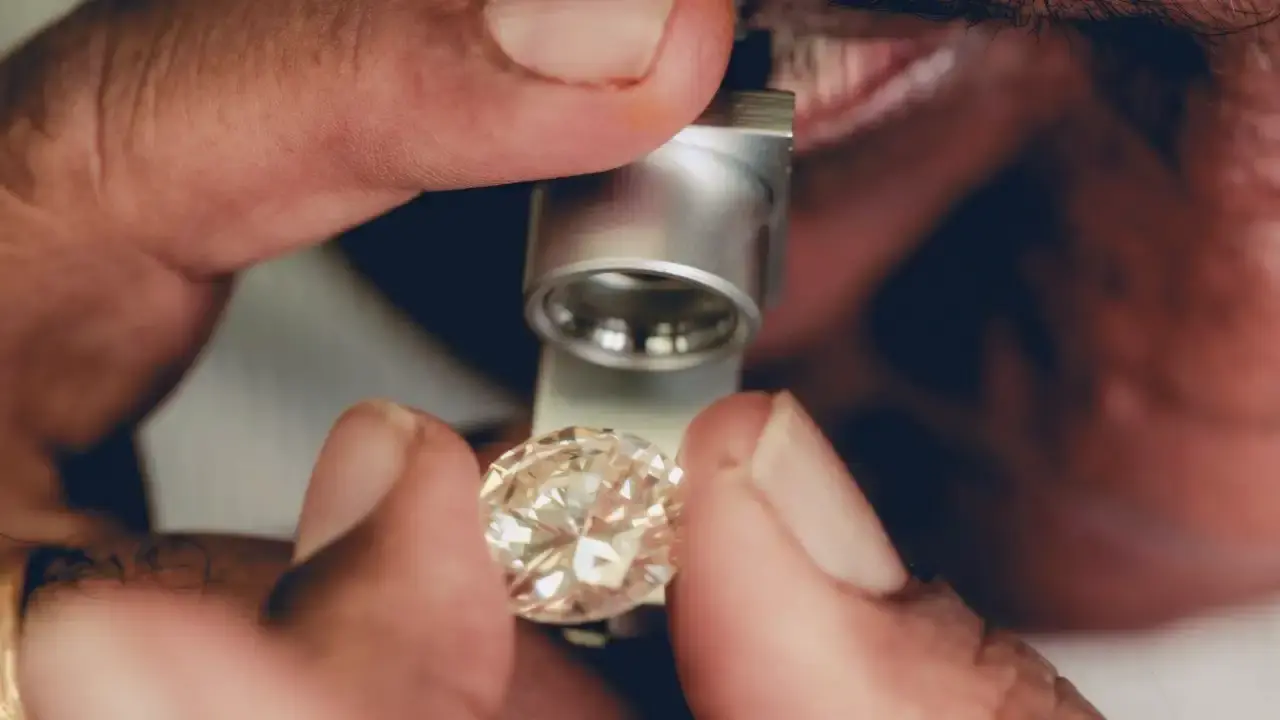 Funcionário usa uma lupa para inspecionar um diamante natural polido em uma oficina no Diamond District de Londres, especializada em joias sob medida