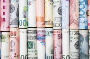 A imagem apresenta diversas notas de diferentes países, enroladas verticalmente e alinhadas lado a lado, exibindo uma colagem colorida que destaca a diversidade monetária global, com variações em valores, ícones e estilo artístico.