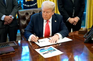 a man sitting at a desk writing on a piece of paper