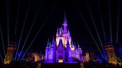 Imagem mostra o Castelo da Cinderela, na Disney, em uma noite. Castelo está iluminado com luz roxa