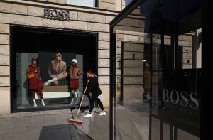 Fachada de uma loja da Hugo Boss, com uma moça varrendo a rua logo em frente