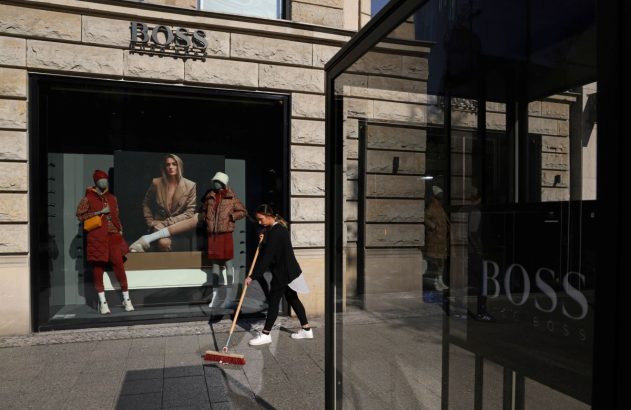 Fachada de uma loja da Hugo Boss, com uma moça varrendo a rua logo em frente