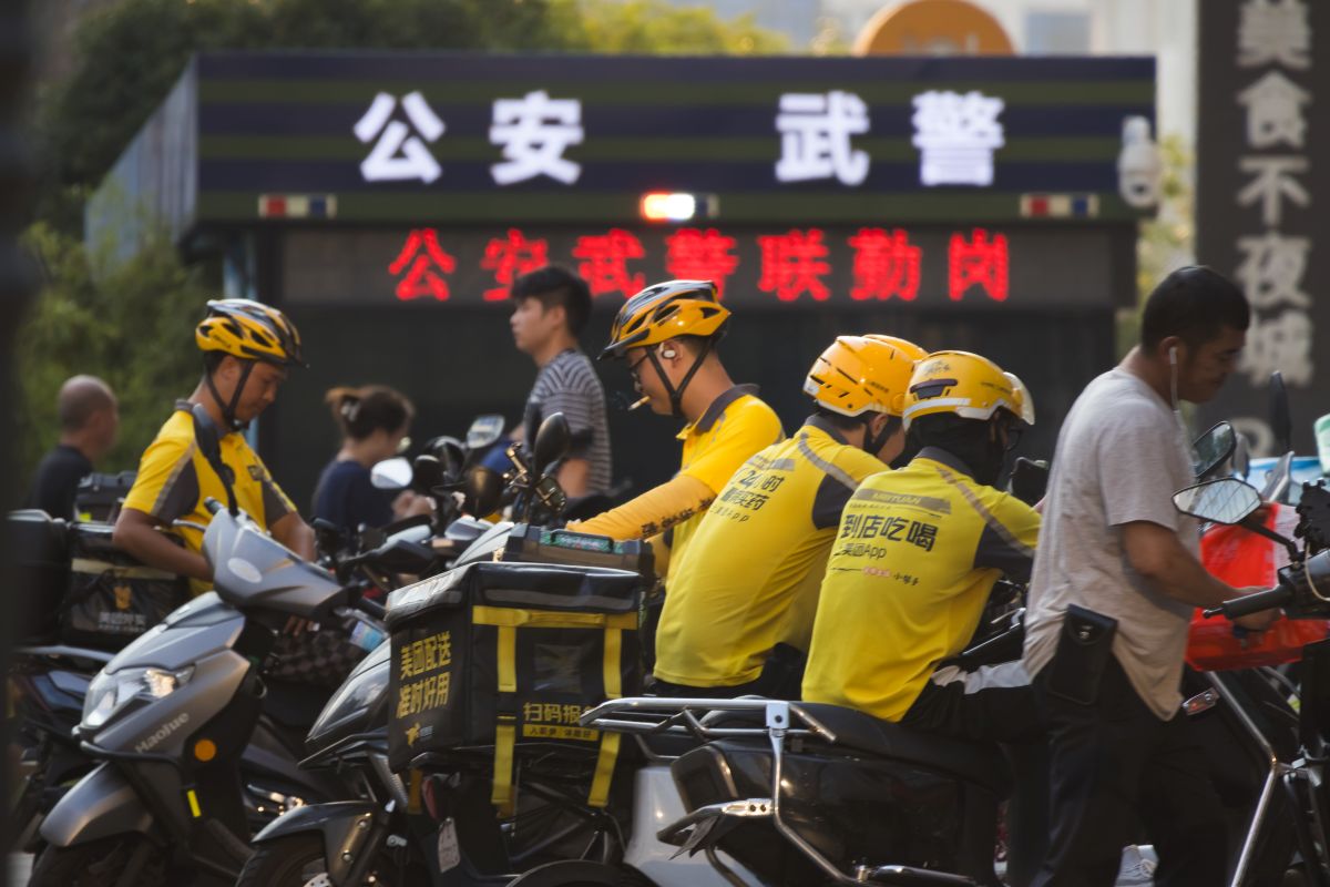 Imagem de entregadores de comida da Meituan, na China, todos de camiseta amarela e capacete amarelo