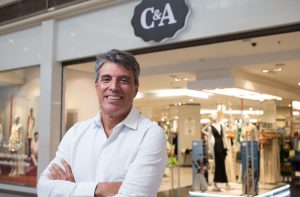 Paulo Correa (homem branco de braços cruzados), CEO da C&A, posa em frente a uma loja
