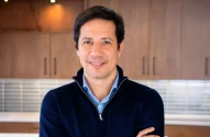 Rafael Oliveira, CEO da JDE Peet's, está com uma blusa azul, de braços cruzados, e sorri para a câmera