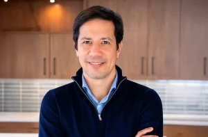 Rafael Oliveira, CEO da JDE Peet's, está com uma blusa azul, de braços cruzados, e sorri para a câmera