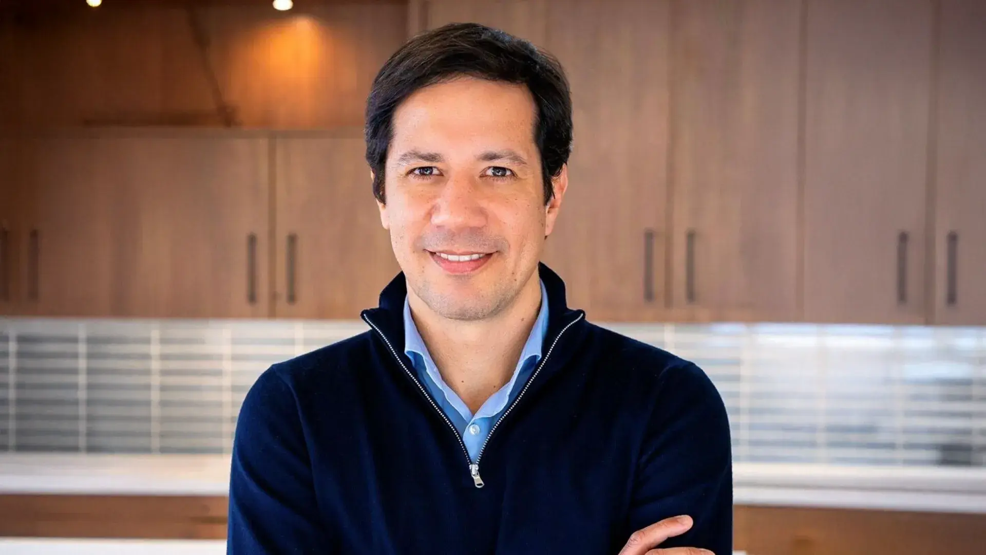 Rafael Oliveira, CEO da JDE Peet's, está com uma blusa azul, de braços cruzados, e sorri para a câmera