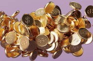A imagem exibe uma pilha de moedas douradas com símbolo de cifrão ($), refletindo luz sobre um fundo lilás, criando um efeito de dinamismo.