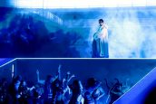 Imagem do cantor Bad Bunny, que está em cima de um palco azul, com a plateia logo abaixo dele