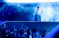 Imagem do cantor Bad Bunny, que está em cima de um palco azul, com a plateia logo abaixo dele