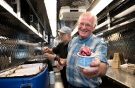 cofundador da Ben & Jerry's, Jerry Greenfield, é um senhor de cabelos brnacos, blusa azul e segura um sorvete vermelho