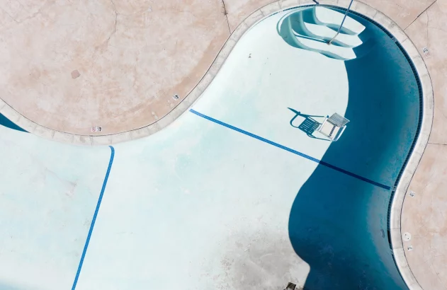 an empty pool with a chair and a ladder
