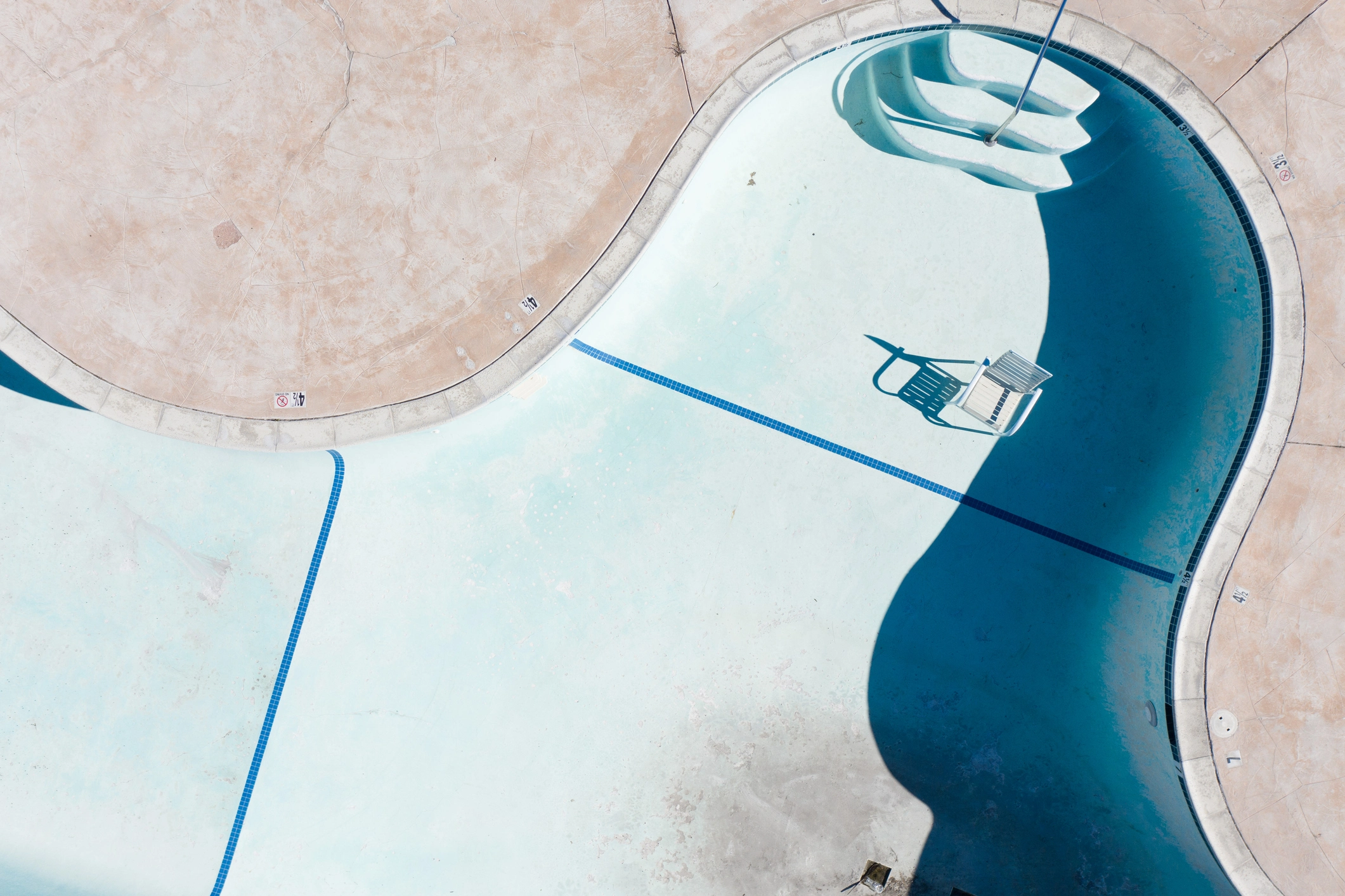 an empty pool with a chair and a ladder