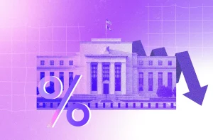 Uma imagem em tons de roxo e rosa mostra a sede do Federal Reserve. À esquerda, há um símbolo de porcentagem e, à direita, uma grande seta apontando para baixo, indicando queda. O fundo tem um padrão quadriculado sutil.