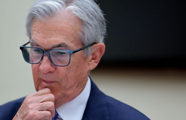 Jerome Powell é presidente do Fed, um senhor de cabelos grisalhos e óculos pretos quadrados, está segurando o queixo, de terno preto e camisa branca